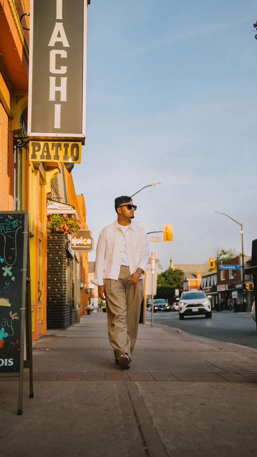 Dev walking past the patio signs on Queen Street South in Streetsville