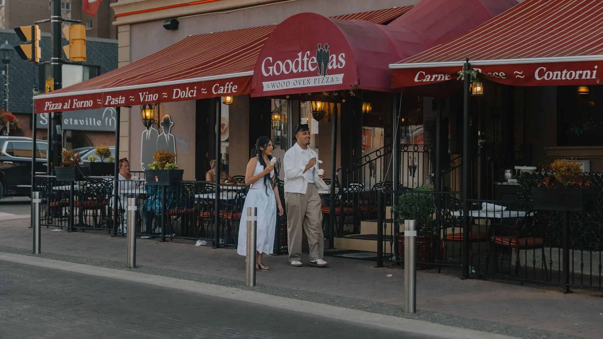 Dev Vashi and his sister walking past the Goodfellas patio on Queen Street South in Streetsville at golden hour