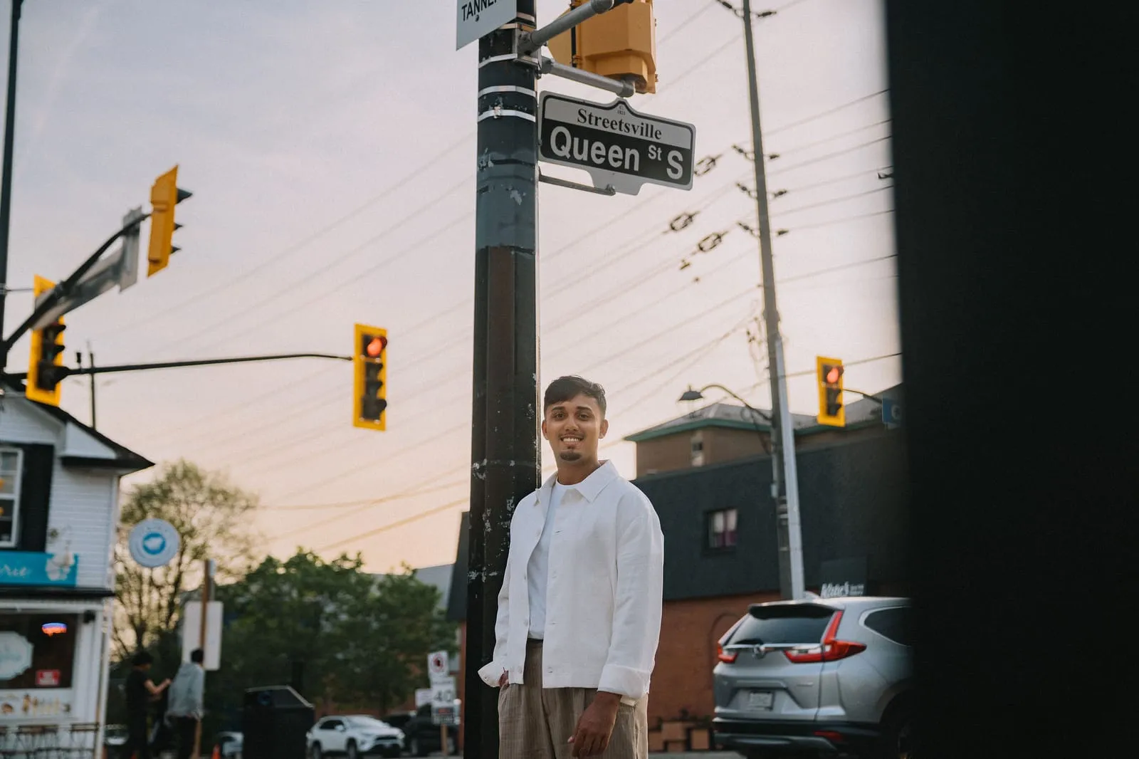 Dev Vashi under the Queen St S sign at a Streetsville intersection at golden hour
