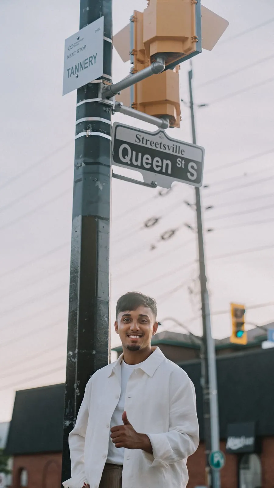 Dev giving a thumbs up under the Streetsville Queen St S street sign